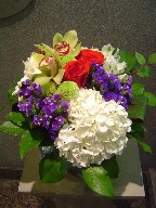 Hydreangea, cymbidium orchids, roses, statice, gerbera, and pompoms