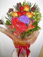 Anthurium, commercial mum, roses, eucadendron, gerbera, lillies, waxflowers, and solidago
