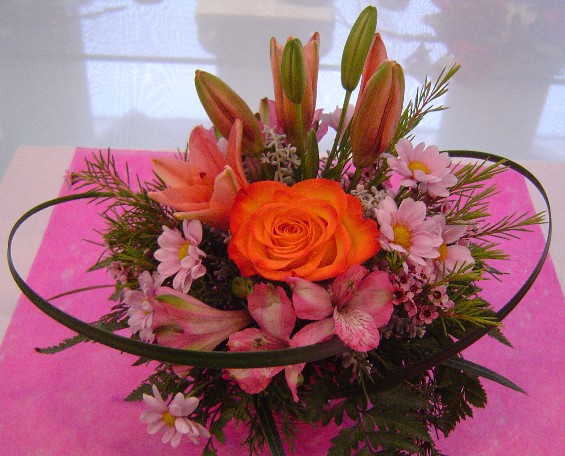 Lilies, rose, alstroemeria, daisies, waxflowers, and monkey grass