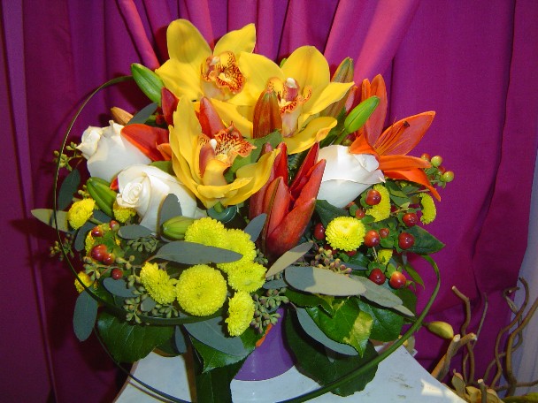 Cymbidium orchids, roses, pompoms, seed eucalyptus, lilies, hypericum, and monkey grass
