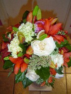 Sedum, orange lillies, ivory roses, and green carnations