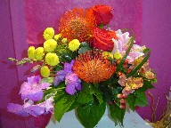 Protea, roses, lillies, orchids, pompoms, alstroemeria, coffee beans, solidago, monkey grass, and variegated pitt