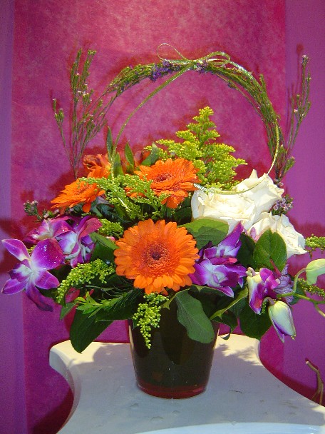 Gerbera, dendrobium orchids, solidago, alstroemeria, roses, and monte casino blue
