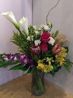 Calla lillies, protea, roses, lisianthus, asiatic lillies, dendrobium orchids, alstroemeria, solidago, monstera, and branch