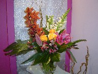 Cymbidium orchids, snapdragon, roses, lillies, alstroemeria, monstera, and curly willow