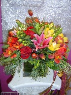Roses, Christmas ornament, Star of Bethlehem, green berries, cymbidium orchids, tulips, lillies, alstroemeria, and pine