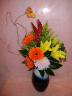 Gerbera, lillies, spider mum, solidago, hypericum, curly willow, and greens