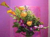 Mango calla lillies, roses, orchids, coffee beans, monkey grass, solidago, and monte casino blue
