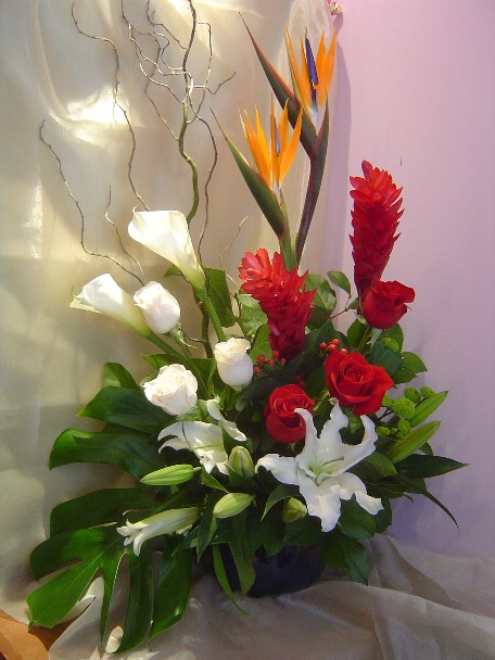 Bird of paradise, ginger, roses, calla lilies, lilies, pompoms, hypericum, and curly willow