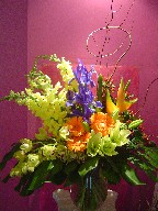 Snapdragon, iris, coffee beans, gerbera, lillies, cymbidium orchids, heliconia, monstera, and curly willow