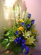 Roses, snapdragon, alstroemeria, lillies, daisies, solidago, and monstera